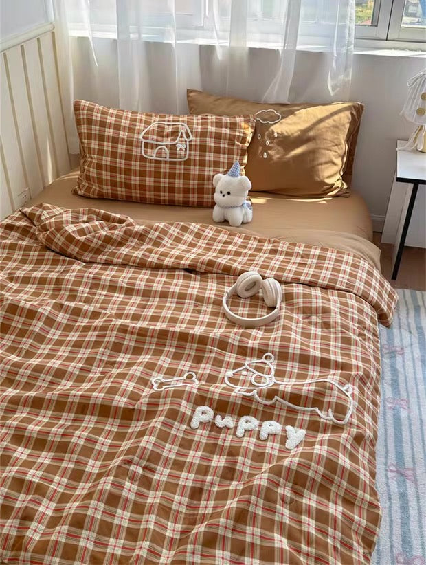 Brown checkered bedding set with 'Puppy' embroidery on a bed in a bright room.
