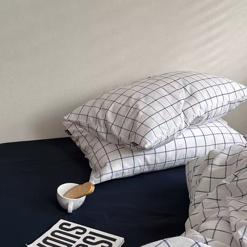 Grid-patterned pillows on a bed with a plain wall background