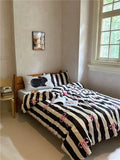 Bedroom with a bed featuring black and white striped bedding with pink accents.