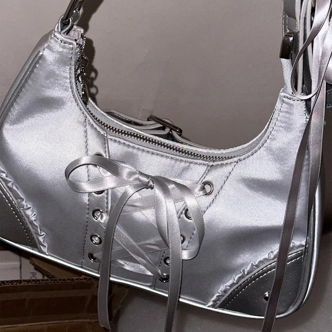 Trendy Y2K underarm bag with soft girl bow detail, styled in aesthetic pastel environment