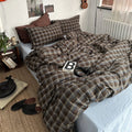 Bed with plaid brown and beige bedding in a bedroom setting.