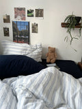 Bedroom with striped bedding, pillows, a teddy bear, and wall decorations.