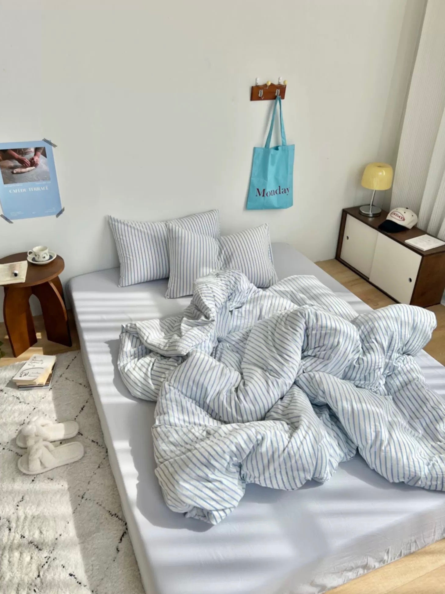 Bedroom with a bed covered in striped bedding, pillows, and a nightstand with a lamp.