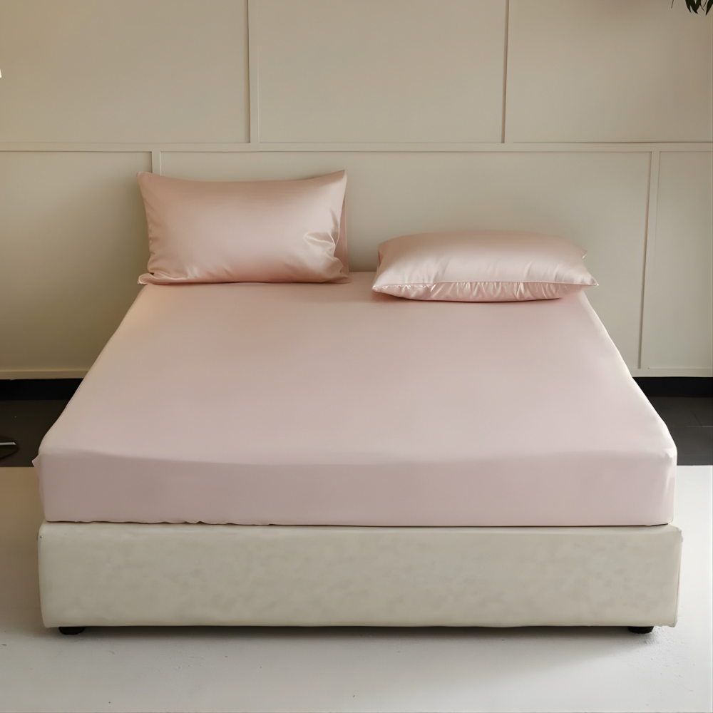Bed with pink bedding and pillows against a neutral wall.