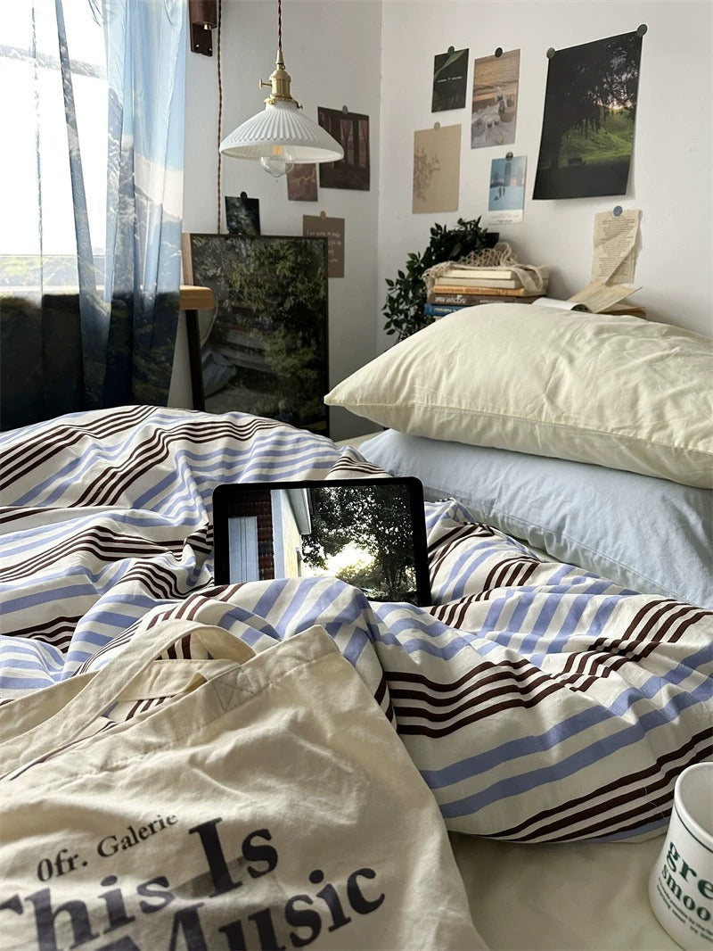 Room with a bed, tablet on striped blanket, and various decor items.