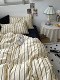 Bedroom with striped bedding and a nightstand with a lamp.
