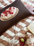 Bedding set with a cake design on a pillow and a striped pattern on the blanket.