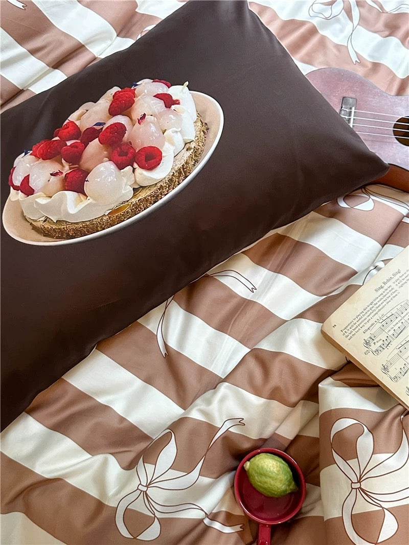 Bedding set with a cake design on a pillow and a striped pattern on the blanket.