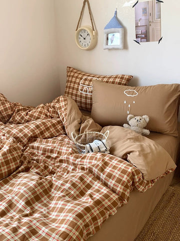 Bed with brown plaid bedding and pillows, teddy bear, and small clock on wall.