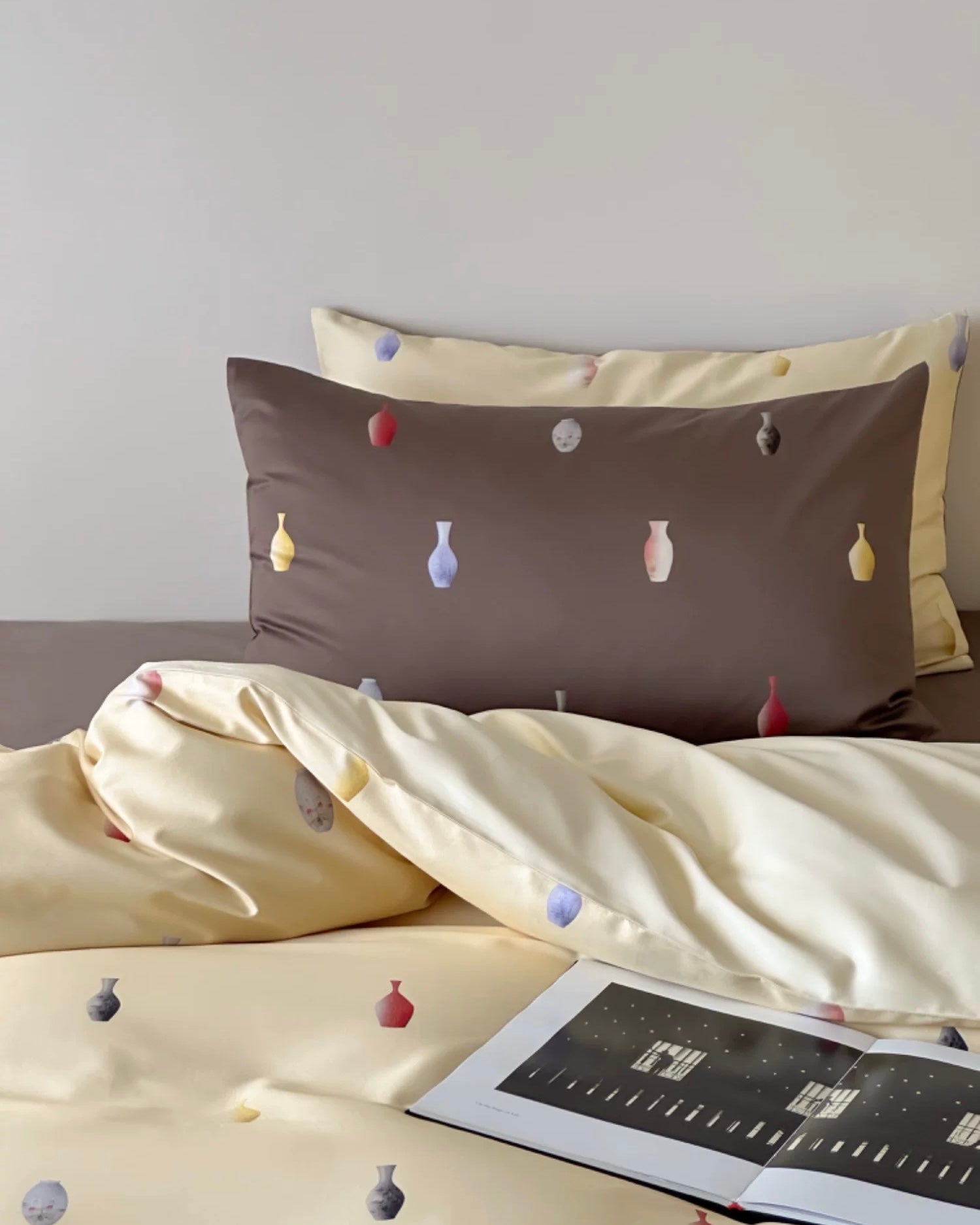 Bedding set with decorative elements on a bed with a tablet on top.
