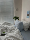 Bedroom with a bed, pillows, and a plant near a window with blinds.