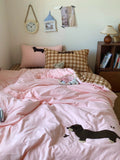 Bedroom with pink bedding featuring dachshund designs, pillows, and a teddy bear.