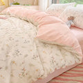 Floral patterned comforter set on a bed with pink accents