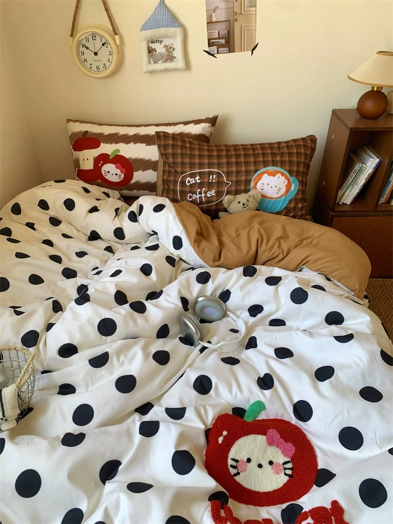 Bed with polka dot comforter and cartoon design, surrounded by decorative pillows and a clock on the wall.