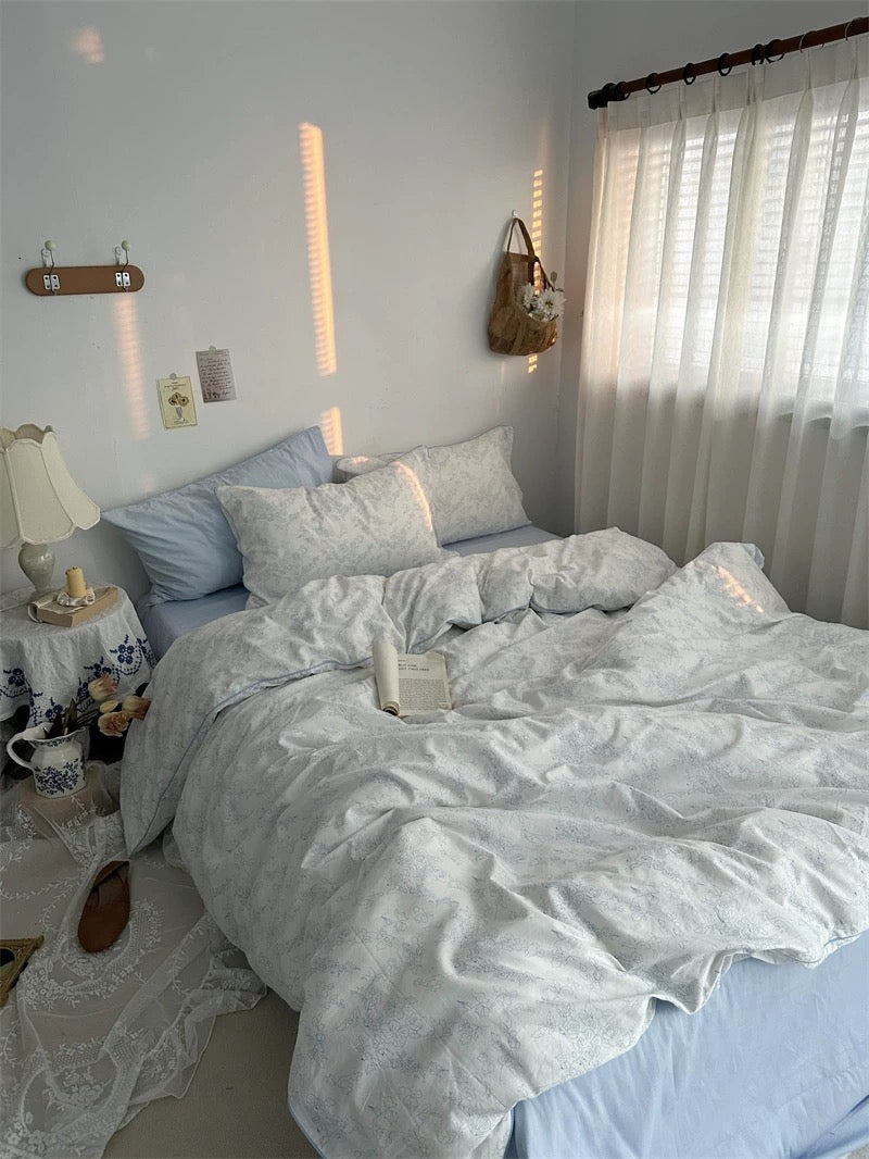 Neatly made bed with light-colored bedding in a bedroom setting.
