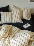 Striped bedding set on a bed with a book and pillow.
