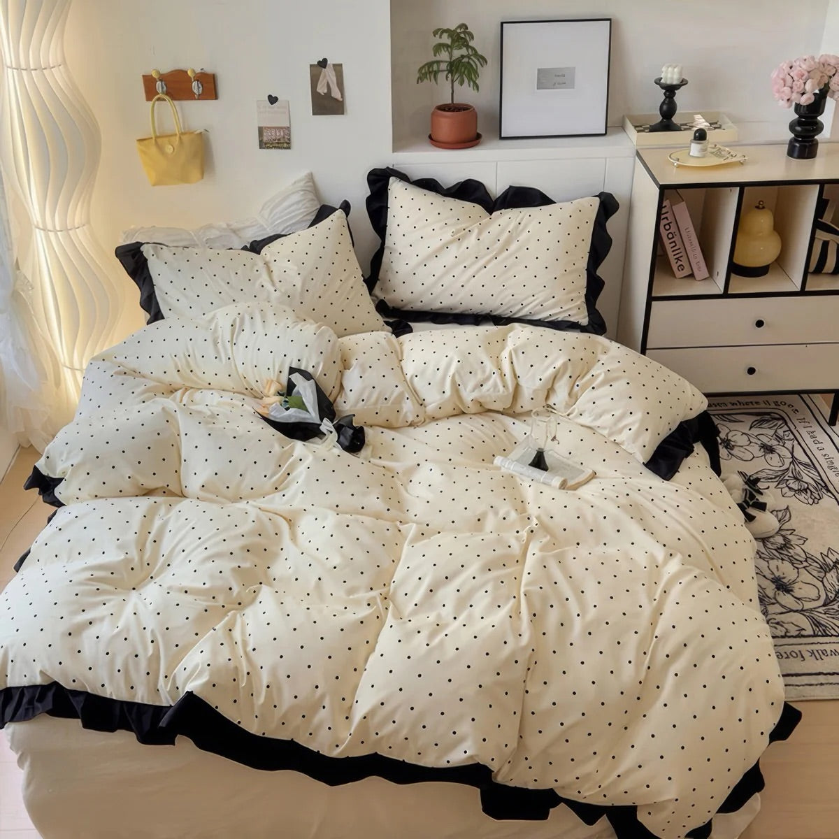 White comforter with black polka dots and trim on a bed in a bedroom setting.