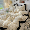 Beige and black polka dot comforter set on a bed with pillows.