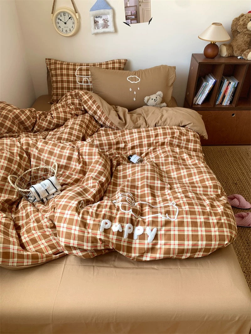 Plaid comforter with 'Pappy' text on a bed in a bedroom setting.
