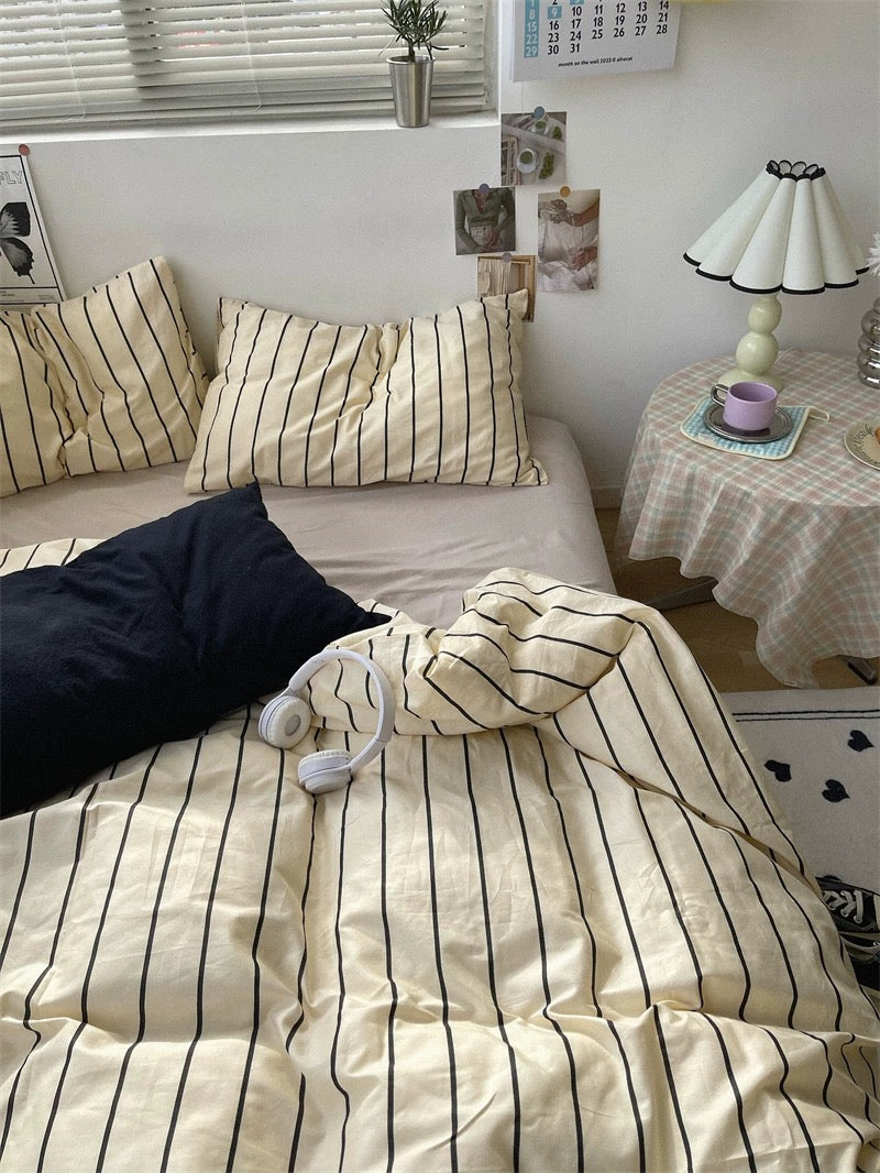 Bed with striped bedding and pillows in a bedroom setting.