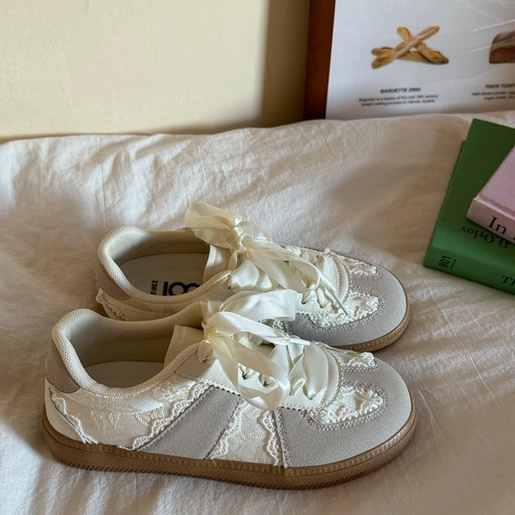 White lace-up sneakers on a white surface with a book in the background