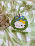 Plush toy with a decorative patch on a green and white checkered fabric