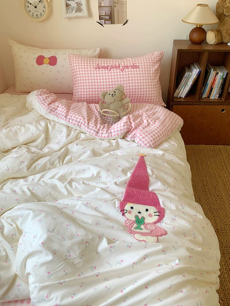 Bed with pink and white checkered blanket, teddy bear, and cartoon character pillow