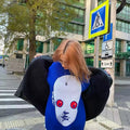 Close-up view of red eyes and pixelated print on blue face sweater for Harajuku fashion