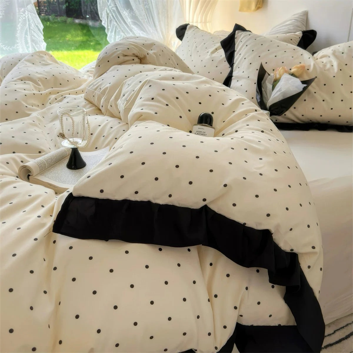 Beige comforter with black polka dots and trim on a bed.