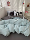 Bed with light blue comforter and cat-themed pillows in a bright room.