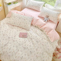Floral bedspread on a bed with a teddy bear and small box in a bedroom setting.