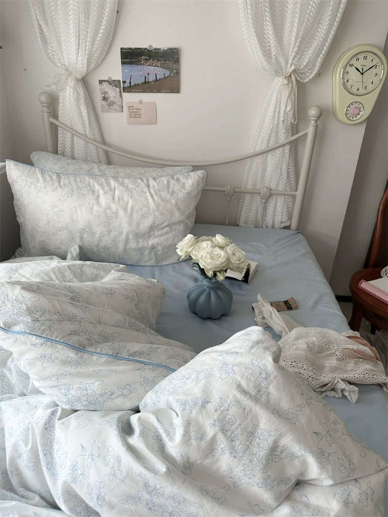 Bedroom with white bedding, pillows, and a vase of flowers on a bed.