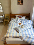 Bed with striped bedding and a pillow in a room with a window and wall art.