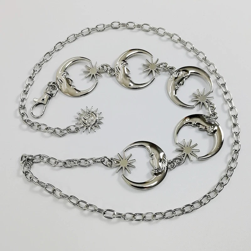 Gold waist chain belt with moon, sun, and star charms styled over a black dress