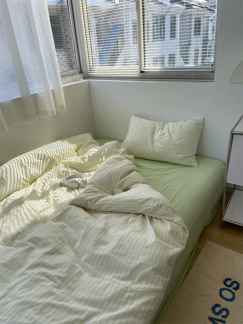 Unmade bed with light-colored bedding in a room with a window.