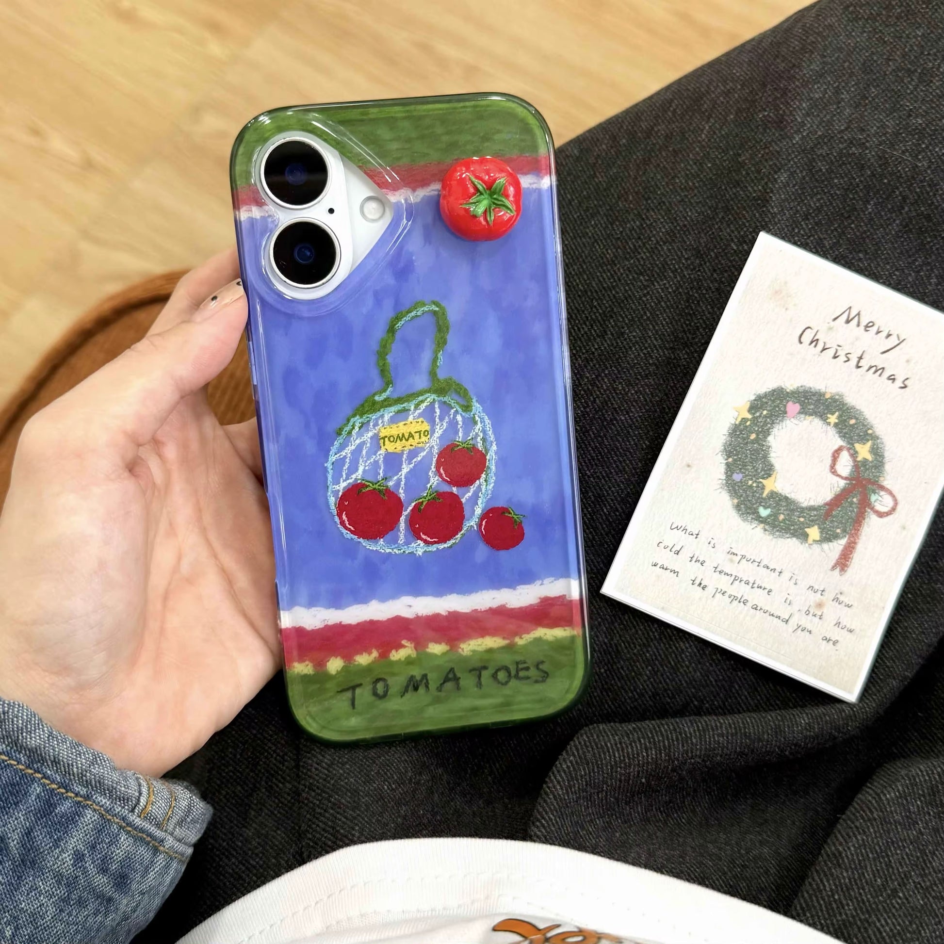 The iPhone case held in hand, demonstrating its ergonomic design and chain functionality