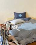 Person sitting on a bed with floral bedding and pillows.