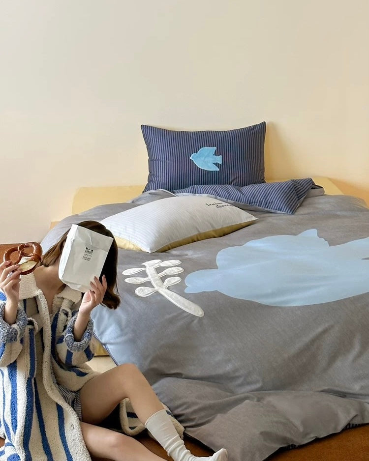 Person sitting on a bed with floral bedding and pillows.