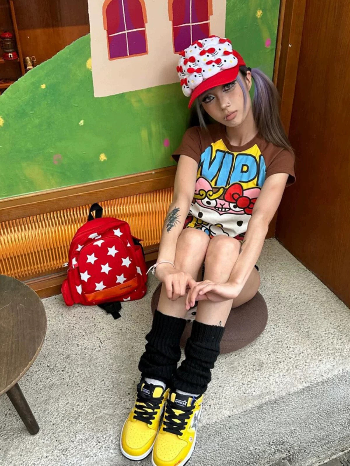 Model sitting outdoors in Harajuku-inspired look wearing the Y2K graphic tee with star backpack.