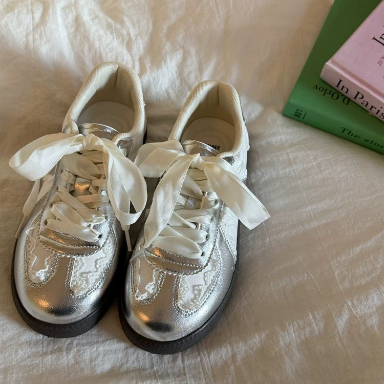 Silver sneakers with white laces on a textured surface