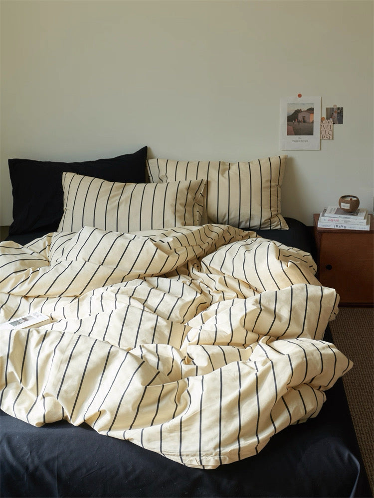Striped bedding on a bed with a nightstand in the background