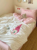 Children's bedroom with pink and white bedding featuring a gnome design, surrounded by decorative pillows and a teddy bear.