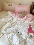 Bed with pink and white checkered blanket, teddy bear, and cartoon character pillow