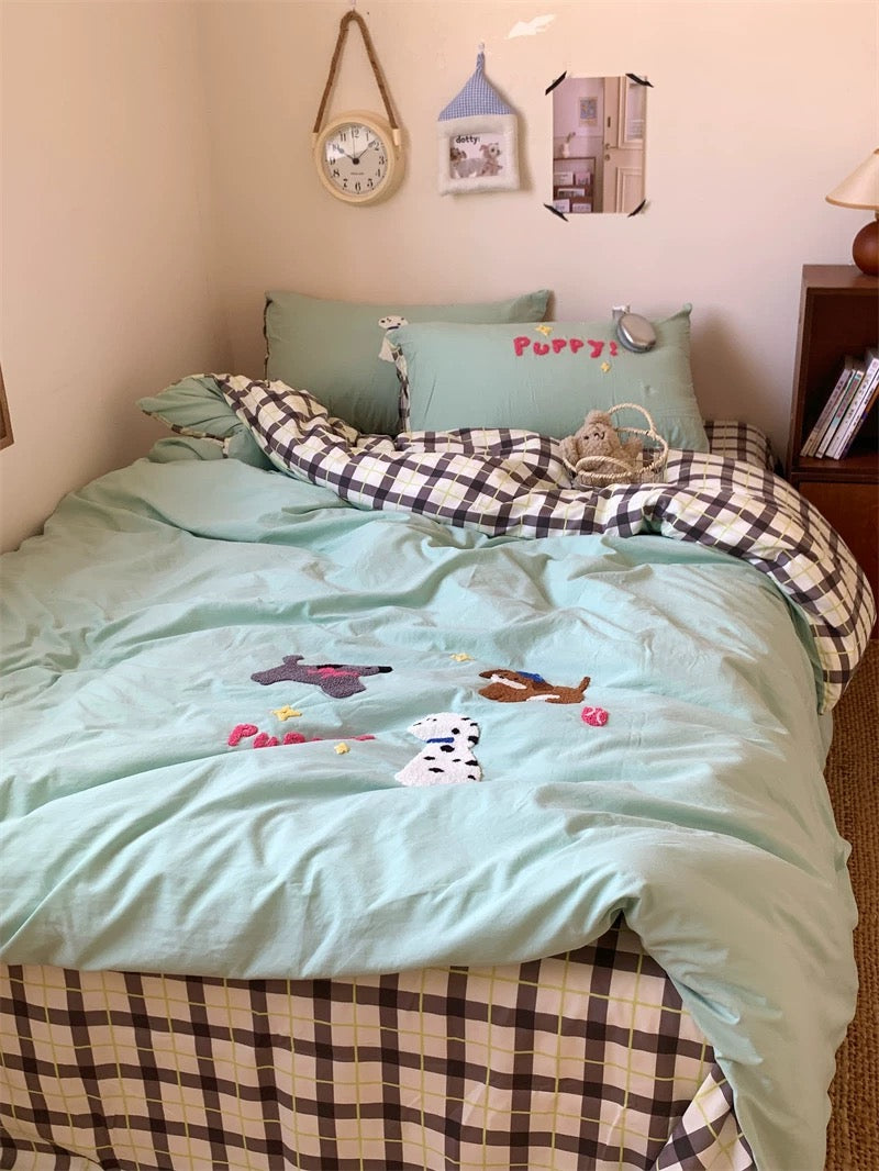 Bed with light blue bedding and checkered blanket, surrounded by decorative items on a shelf.