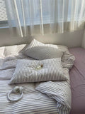 Bed with striped bedding and pillows in a softly lit room.