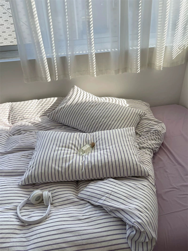 Bed with striped bedding and pillows in a softly lit room.