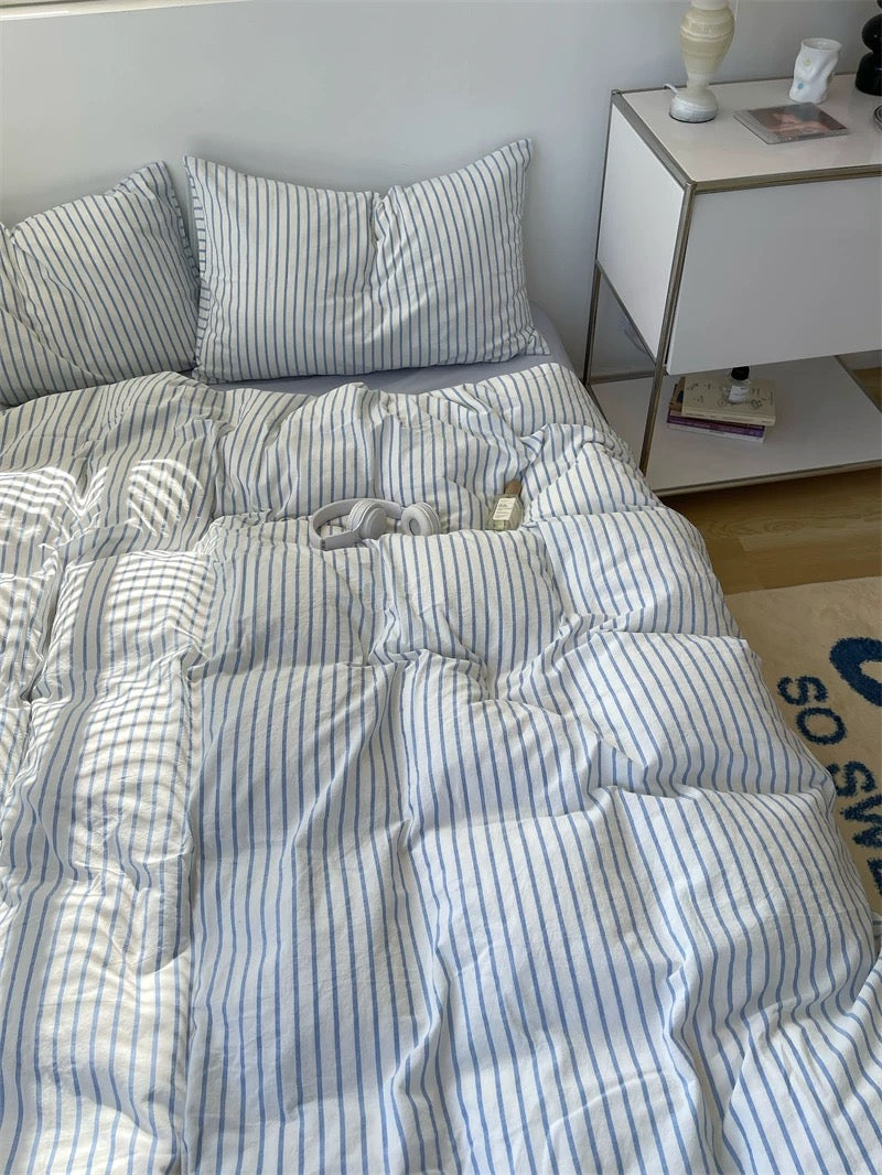 Striped bedding on a bed with a nightstand in the background
