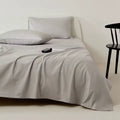 Gray bedding set on a bed with a minimal background