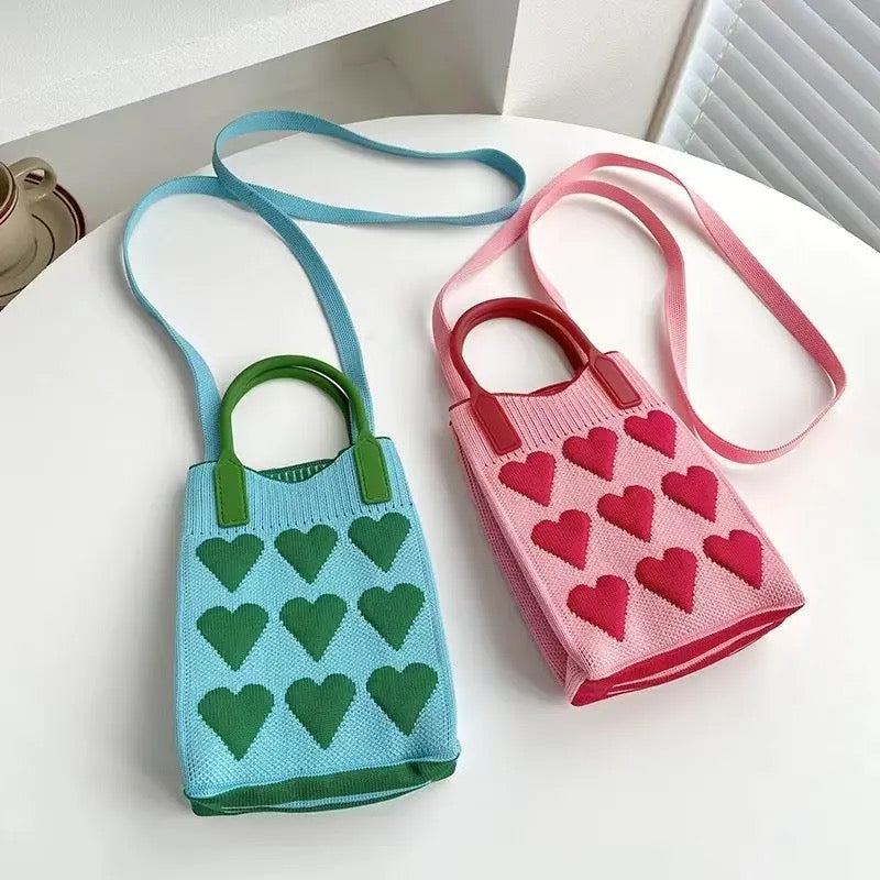 Compact knitted heart handbag on white background