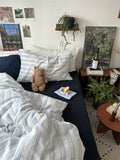 Living room with a couch, pillows, a teddy bear, and a bottle of wine.